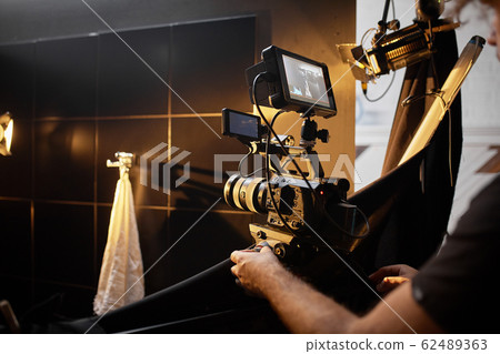 Video production backstage. Behind the scenes of creating video content, a professional team of cameramen with a director filming commercial ads. Video content creation, video creation industry. Low 62489363