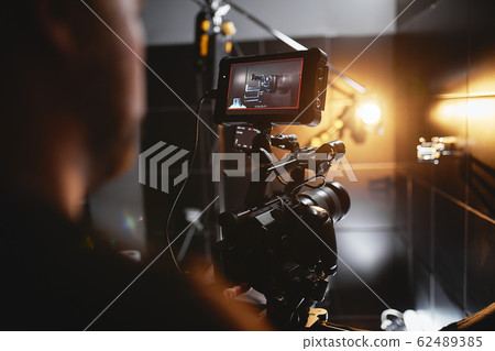 Video production backstage. Behind the scenes of creating video content, a professional team of cameramen with a director filming commercial ads. Video content creation, video creation industry. Low 62489385
