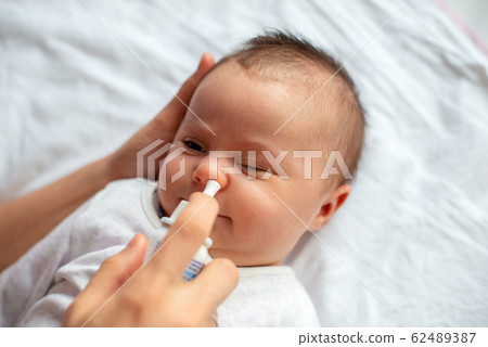 Woman using nasal spray for baby 62489387