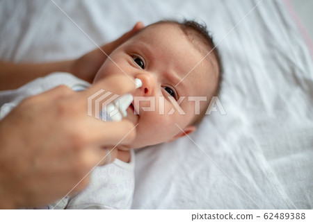 Woman using nasal spray for baby Woman using nasal spray for baby 62489388