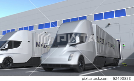 Modern semi-trailer trucks with MADE IN IRELAND text being loaded or unloaded at warehouse. Turkish business related 3D rendering 62490828