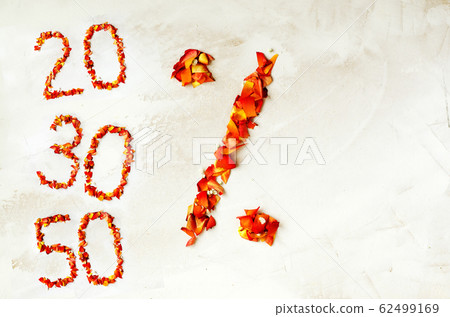 Symbol percent from rose petals. Percent symbol made of yellow-red rose petals isolated on a white background. On the left side, the denominations of twenty, thirty and fifty are laid out from rose 62499169