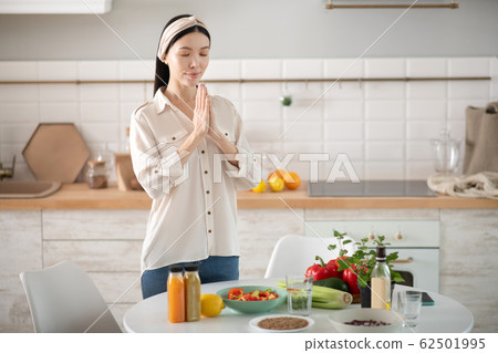 Young asian girl standing, closing her eyes, clasped her hands. Young asian girl standing, closing her eyes, clasped her hands. 62501995
