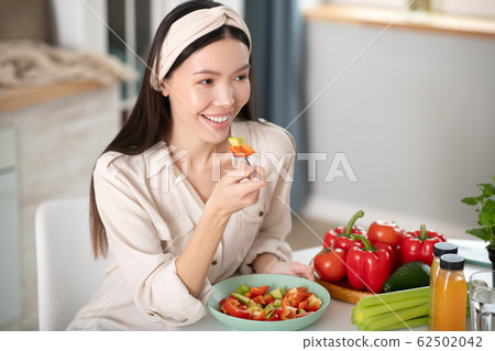 Good looking young woman sitting eating salad. 62502042