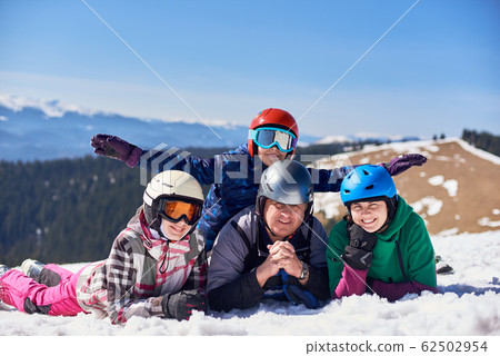 Happy smiling family on skis and snowboard in deep snow on background of winter mountains. 62502954