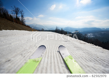 Skis on white snowy ski track, winter mountain landscape and blue sky copy space background. 62502970