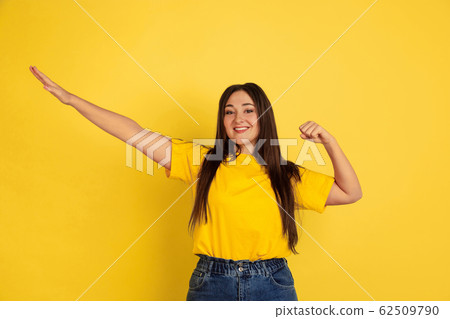 Caucasian woman's portrait isolated on yellow studio background 62509790