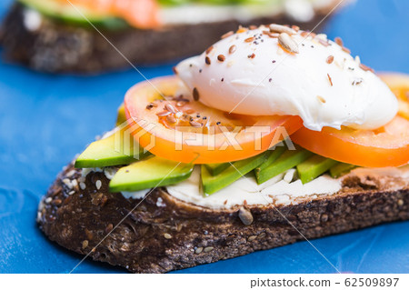 Sandwich with smoked salmon, egg and avocado on blue background. Concept for healthy nutrition. 62509897