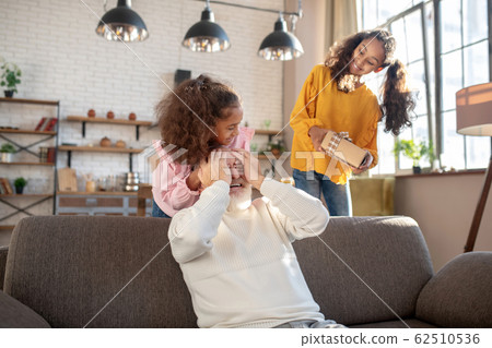 Cute dark-skinned girls making a surprise for their granddad Cute dark-skinned girls making a surprise for their granddad 62510536