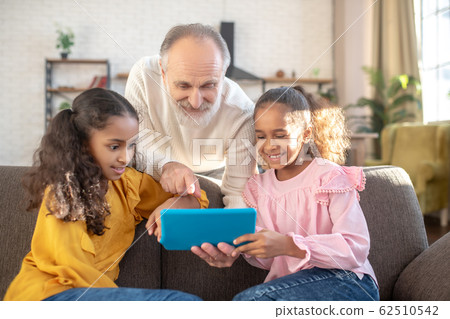 Bearded man in a white shirt pointing to the tablets screen Bearded man in a white shirt pointing to the tablets screen 62510542