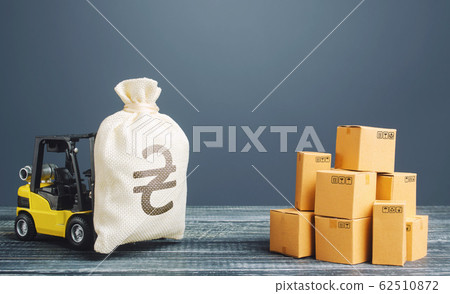 Forklift truck carries ukrainian hryvnia money bag near pile of boxes. Profit from trade and exchange of goods. Investments financing in production, taxes, income revenues and costs. Superprofits. Forklift truck carries ukrainian hryvnia money bag near pile of boxes. Profit from trade and exchange of goods. Investments financing in production, taxes, income revenues and costs. Superprofits. 62510872