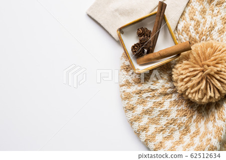 Knitted hat and Pine cones and cinnamon sticks in a bowl on white background. Autumn concept Knitted hat and Pine cones and cinnamon sticks in a bowl on white background. Autumn concept 62512634