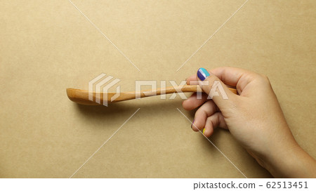 Wooden spoon with hand on brown background Wooden spoon with hand on brown background 62513451