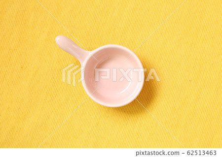 Pink ceramic bowl on yellow fabric background Pink ceramic bowl on yellow fabric background 62513463