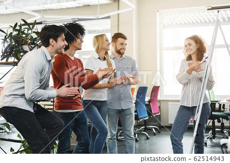 Positive team cheering female colleague making presentation 62514943