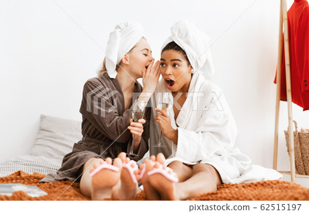 Cheerful multiethnic girlfriends sharing gossips while making pedicure Cheerful multiethnic girlfriends sharing gossips while making pedicure 62515197