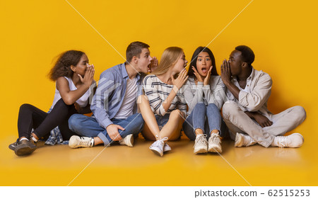 Group of multiracial friends gossiping over yellow background 62515253