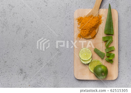 A powder of turmeric, sliced Aloe vera and lime on a wood 62515305