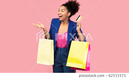 Portrait of cheerful afro girl holding shopping bags looking away 62515571