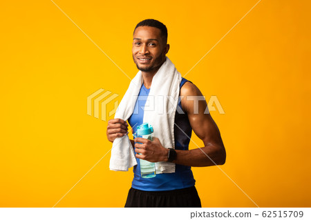 Afro sportsman with towel holding a bottle of water 62515709