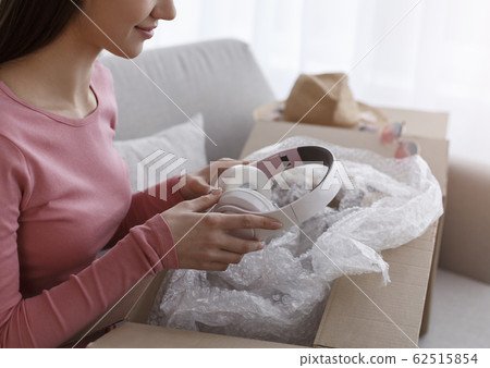 Woman unpacking her online order in the living room 62515854