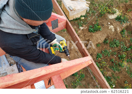 A man fastens two wooden beams with a self-tapping A man fastens two wooden beams with a self-tapping 62516221