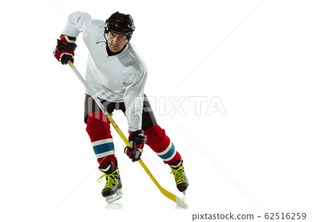Young male hockey player with the stick on ice court and white background 62516259