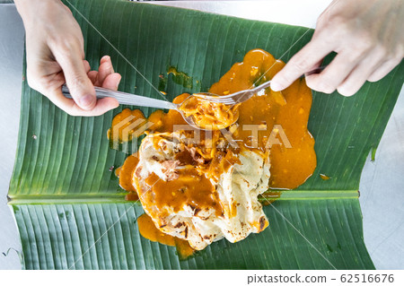 Person eating roti canai or paratha with curry on Person eating roti canai or paratha with curry on 62516676