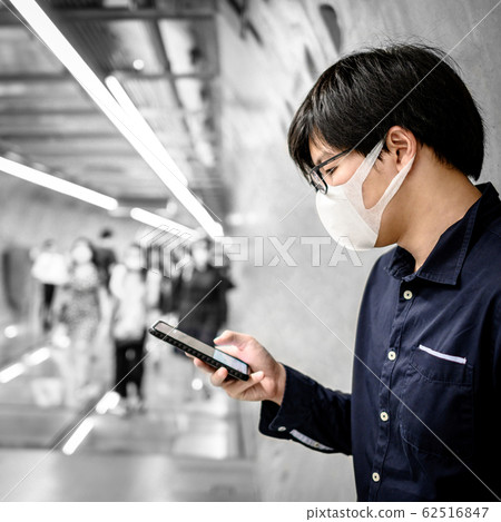 Asian man wearing mask using phone in subway 62516847
