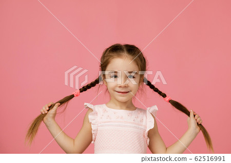 Cute small child girl holding long hair braids Cute small child girl holding long hair braids 62516991