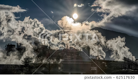 Smoking chimneys. Smoke from smokestack and shinning sun in factory Mondi, Ruzomberok , Slovakia. Air pollution concept 62517630