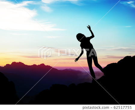 Black silhouette of woman walking down of rock. 62517755