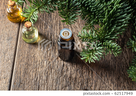 A dropper bottle of essential oil with fresh fir branches 62517949