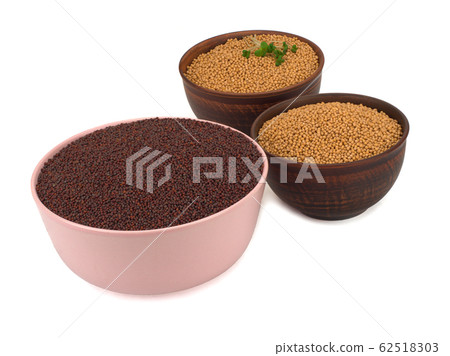 Mustard seeds black and white in plates isolated on a white Mustard seeds black and white in plates isolated on a white 62518303