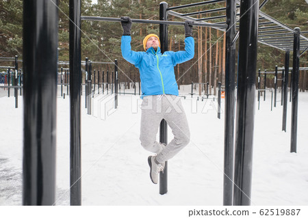 Doing pull-ups on outdoor bar 62519887