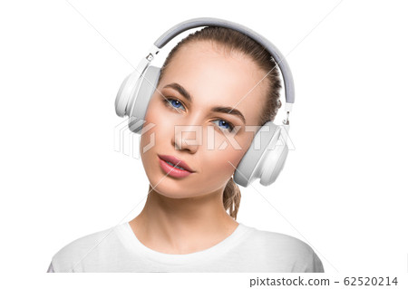 Blue eyed woman in headphones looking at camera. Close up portrait. Blue eyed woman in headphones looking at camera. Close up portrait. 62520214