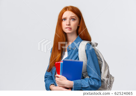 Worried cute and nervous redhead teenage girl scared parents scold her for skipping class, biting lip anxiously looking camera, holding notebooks and backpack over white background Worried cute and nervous redhead teenage girl scared parents scold her for skipping class, biting lip anxiously looking camera, holding notebooks and backpack over white background 62524065
