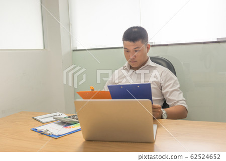 Asian businessman reading financial reports Asian businessman reading financial reports 62524652