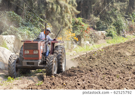 Man preparing the land for harvest with the 62525792