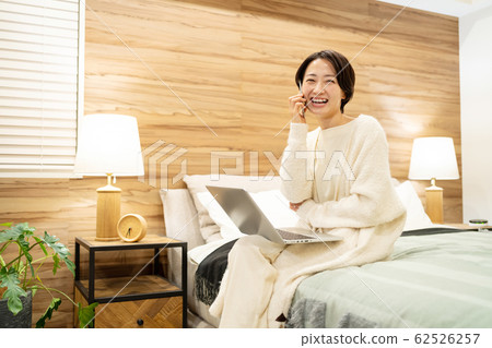Middle woman bedroom smartphone personal computer lifestyle image Middle woman bedroom smartphone personal computer lifestyle image 62526257