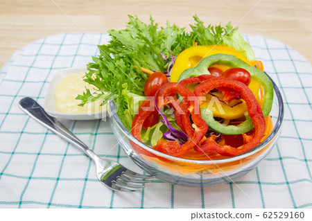 Close up A green salad is a dish of a mixture of small vegetables, Cucumbers fragrant vegetables tomatoes peppers corn carrots on wood table. Close up A green salad is a dish of a mixture of small vegetables, Cucumbers fragrant vegetables tomatoes peppers corn carrots on wood table. 62529160