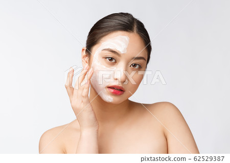 Charming pleasant woman applying cream on half face Charming pleasant woman applying cream on half face 62529387