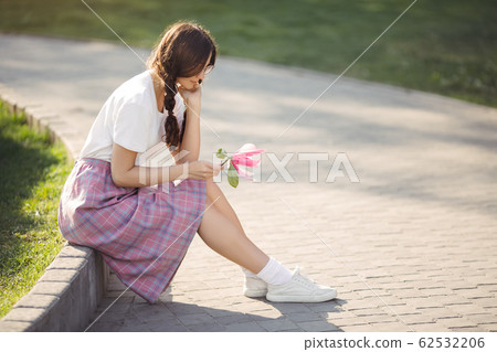Woman with Flower Outdoors in the City Park Woman with Flower Outdoors in the City Park 62532206