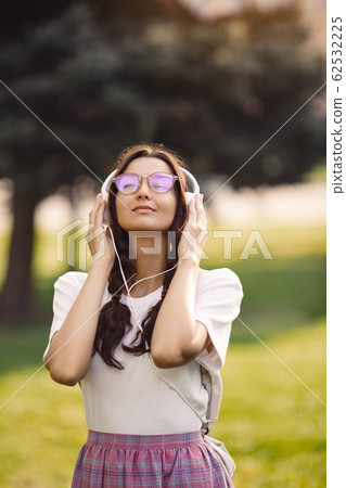 Woman With Headphones Outdoors in the City Park Woman With Headphones Outdoors in the City Park 62532225