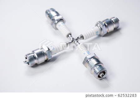 Subject shooting on a gray background. new four spark plugs, spare parts for a gasoline engine. The concept of new auto parts and maintenance Subject shooting on a gray background. new four spark plugs, spare parts for a gasoline engine. The concept of new auto parts and maintenance 62532283