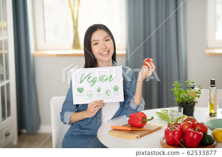 Good looking woman with poster and red tomato in her hands. 62533877