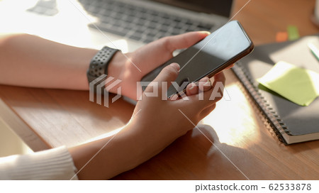 Cropped shot of a woman using smartphone in simple 62533878