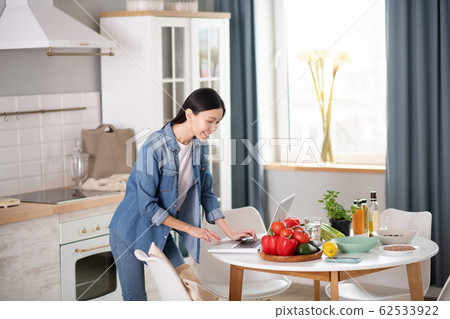 Young girl near laptop, on the table vegetarian products. 62533922