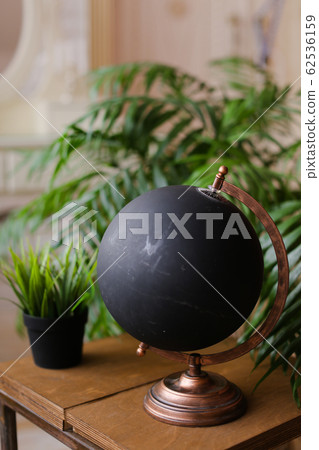 Black globe standing on wooden table near houseplants. Black globe standing on wooden table near houseplants. 62536159