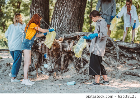 Group of activists friends collecting plastic waste on the beach. Environmental conservation. 62538123
